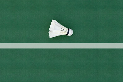 A dynamic shot of a badminton racket and shuttlecock resting on a clean, minimalist court surface.