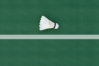 A dynamic shot of a badminton racket and shuttlecock resting on a clean, minimalist court surface.