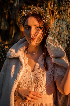 An elegant Queen of Pentacles tarot card surrounded by flourishing greenery and golden coins, bathed in soft, warm light.