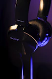 Close-up of wireless headphones with blue LED highlights on a black surface