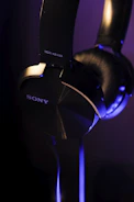 Close-up of wireless headphones with blue LED highlights on a black surface