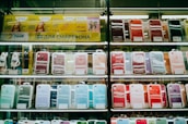 Shelves display a variety of smartphone cases in multiple colors, arranged in an organized manner within a store. A sign in Cyrillic characters and advertisements for mobile network plans are visible above the cases.
