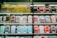 Shelves display a variety of smartphone cases in multiple colors, arranged in an organized manner within a store. A sign in Cyrillic characters and advertisements for mobile network plans are visible above the cases.
