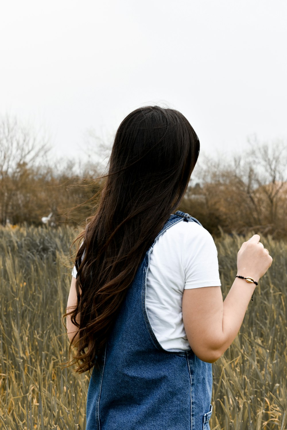 woman in white t-shirt and blue denim jeans sitting on grass field during daytime