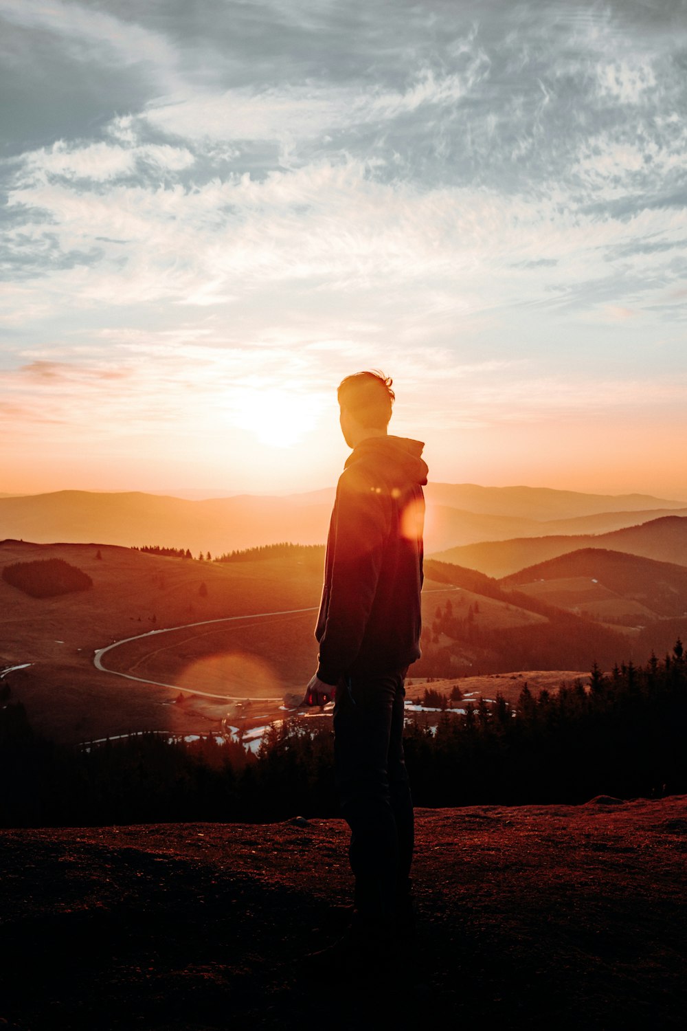 silhouette d’homme debout sur la montagne pendant le coucher du soleil