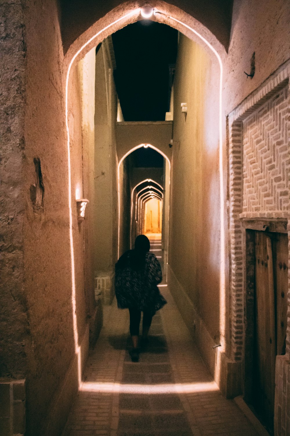 person in black coat walking on hallway