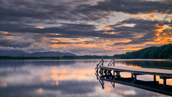 brown wooden dock on lake during sunset