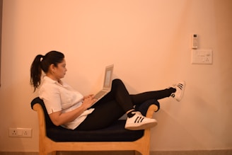 woman in white dress shirt and black pants sitting on brown wooden chair