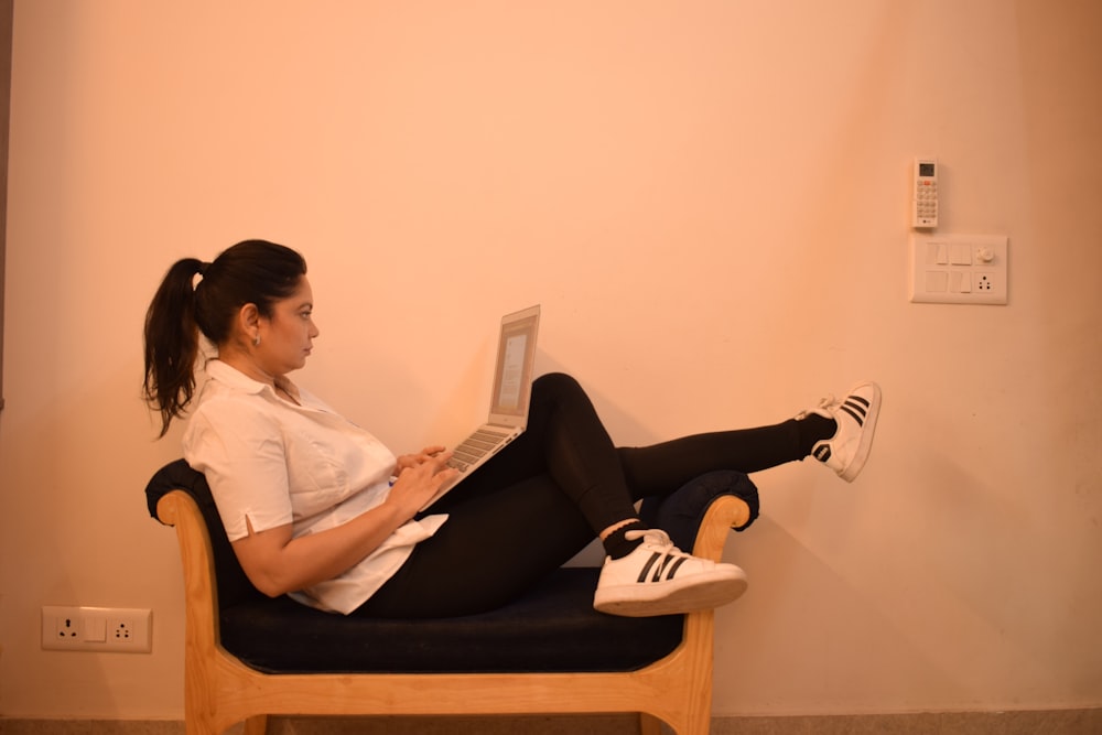 woman in white dress shirt and black pants sitting on brown wooden chair