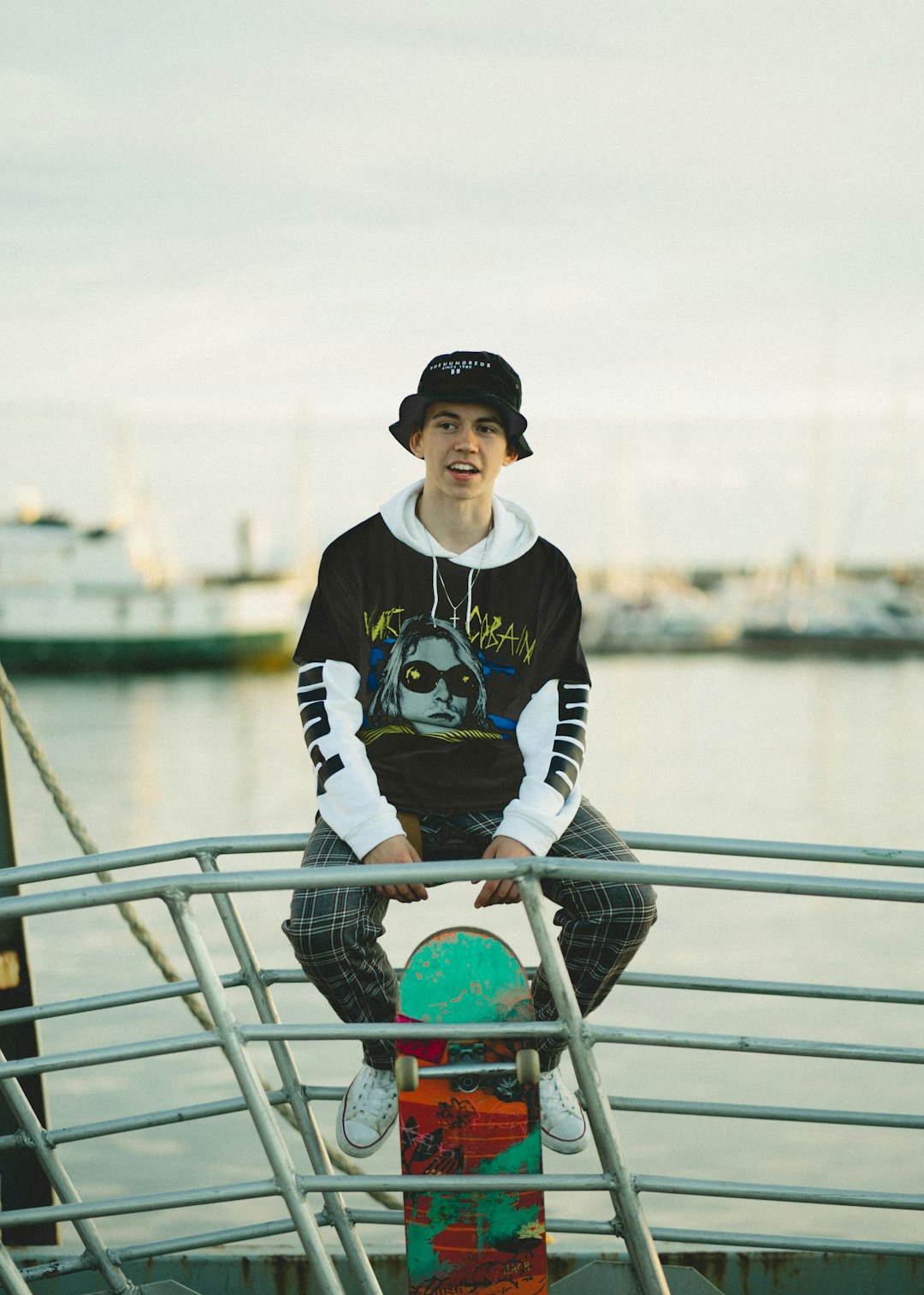 man in black and white sweater sitting on gray metal railings during daytime