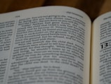 An open book with visible text focused on a passage from the Old Testament. The font is clear and the text is black against a white background. The right margin of the page is visible, and the book lies on a wooden surface.