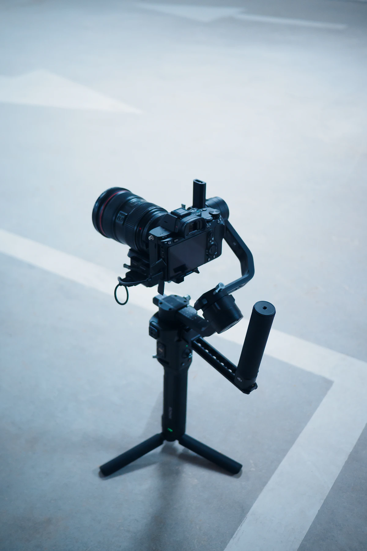 A camera mounted on a gimbal stabilizer, standing on its tripod legs
