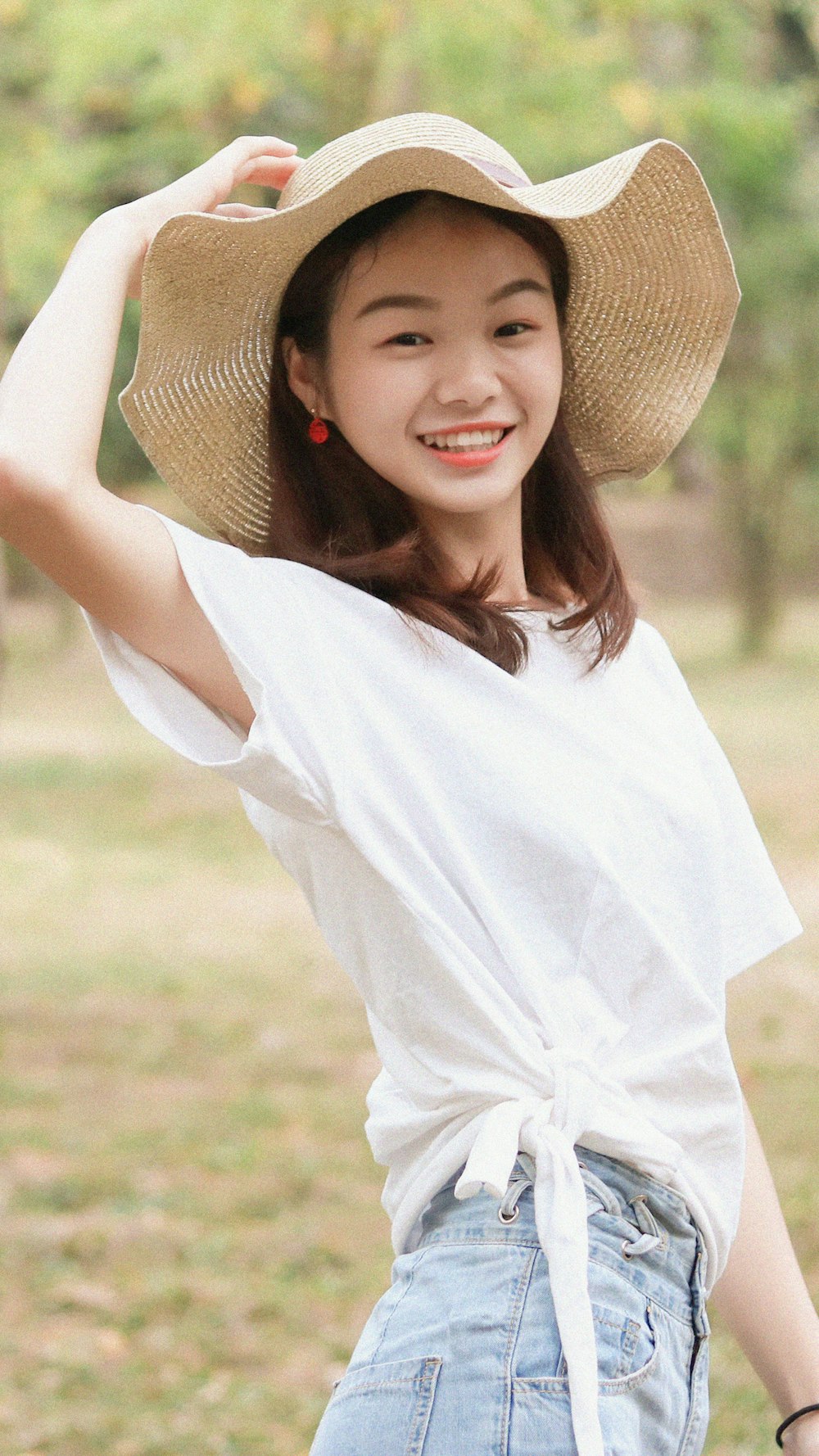 茶色の麦わら帽子をかぶった白いシャツの女性