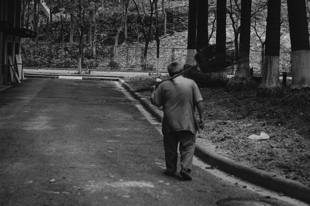 grayscale photo of man walking on pathway