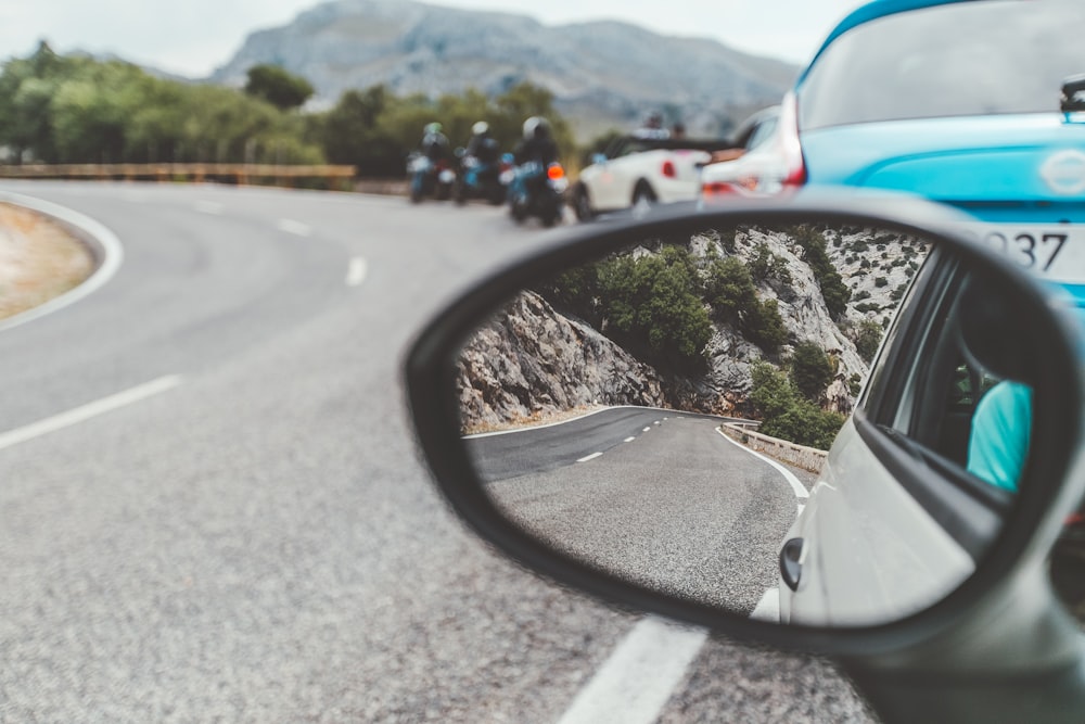 black car side mirror showing cars on road during daytime