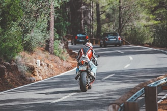 man in red and white motorcycle suit riding motorcycle on road during daytime