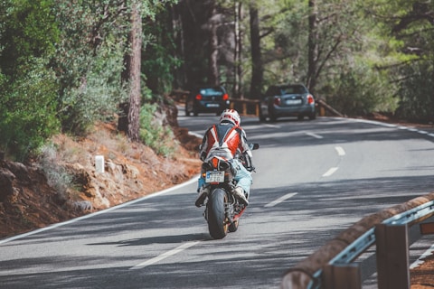 man in red and white motorcycle suit riding motorcycle on road during daytime