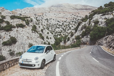 A serene mountain landscape with a rental car parked beside a winding road.