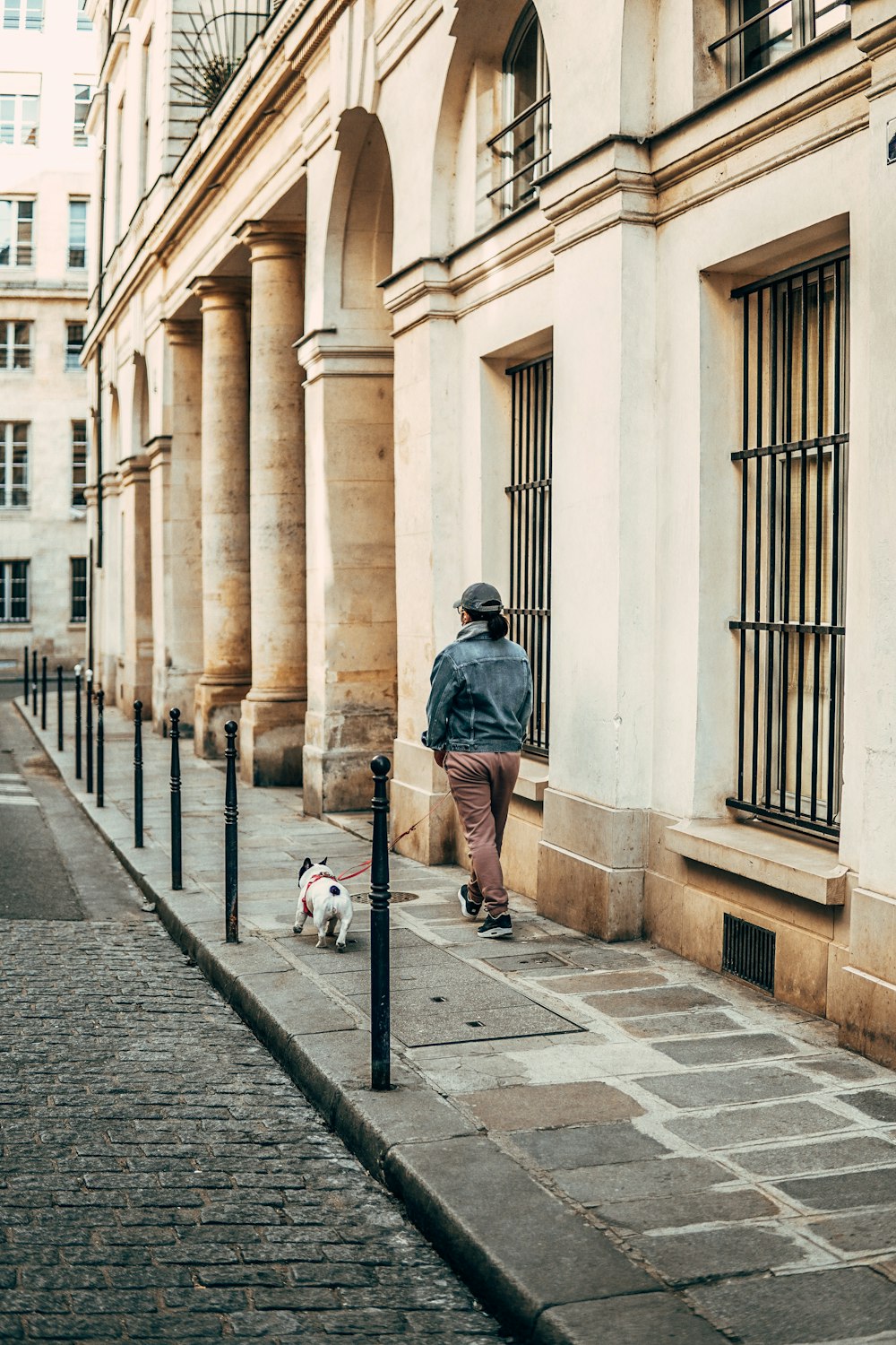 man in blue denim jacket walking on sidewalk during daytime