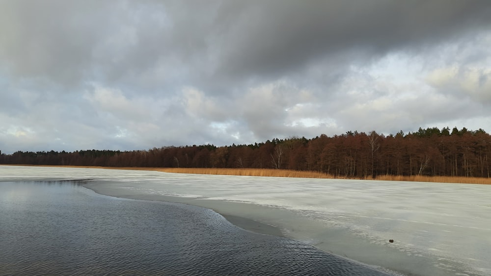 snow covered field under cloudy sky during daytime