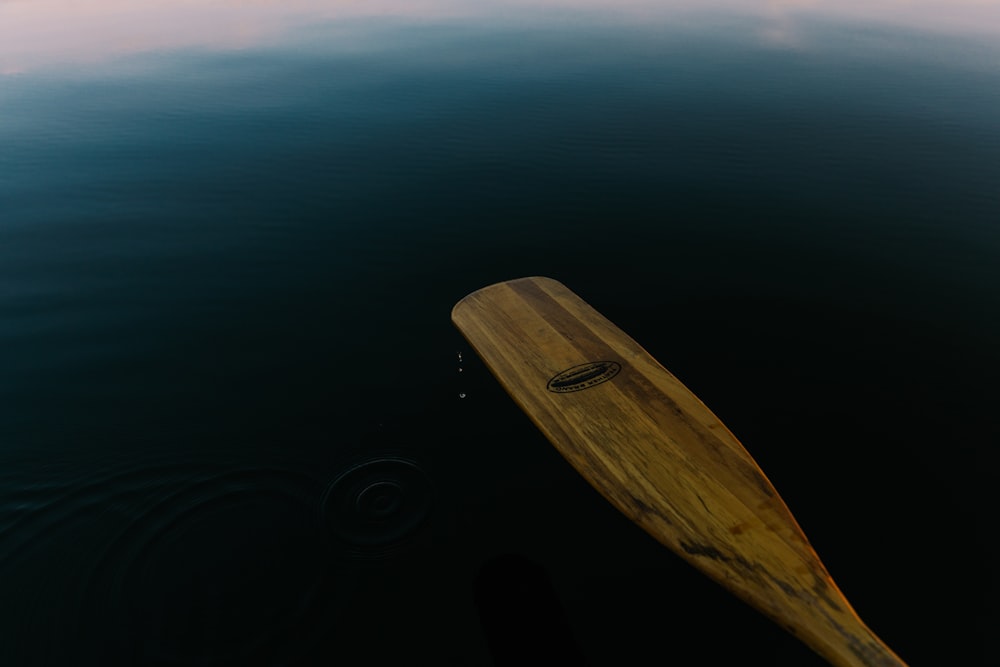 brown wooden paddle on body of water