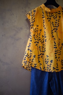 A vibrant, patterned blouse paired with classic jeans, hanging on a rustic rack with greenery nearby