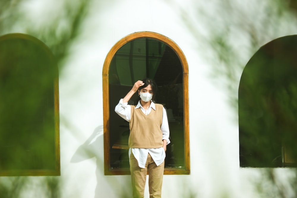 man in white dress shirt and brown pants standing beside brown wooden door