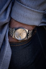 person wearing silver link bracelet round analog watch