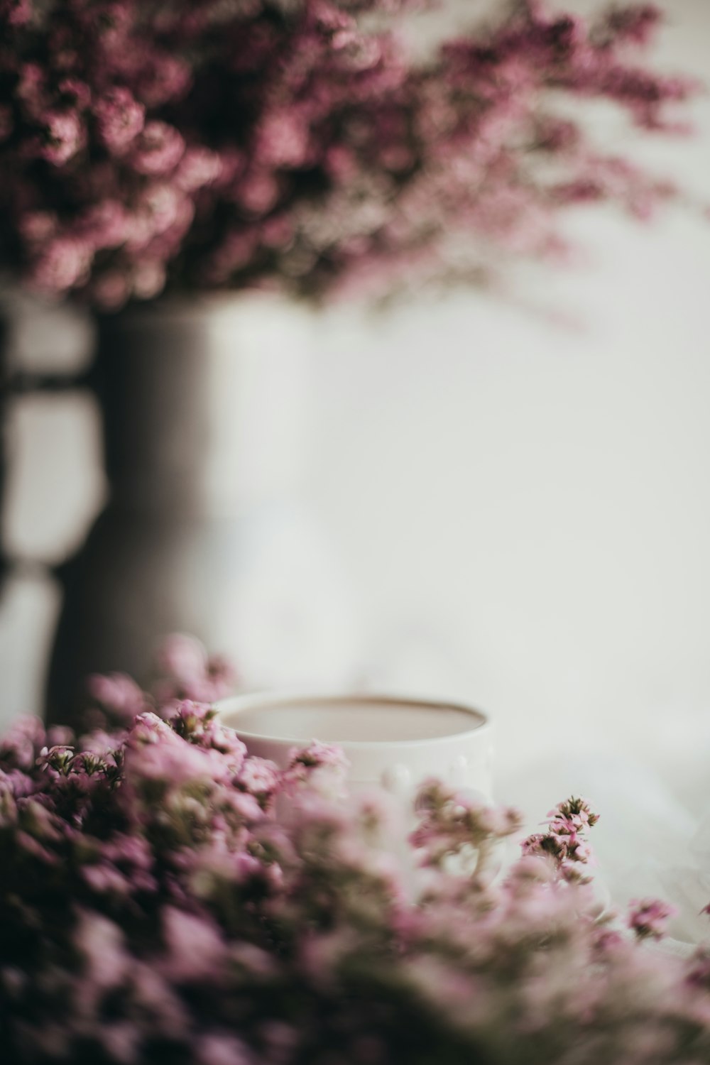 흰색 세라믹 머그잔 옆에 보라색 꽃