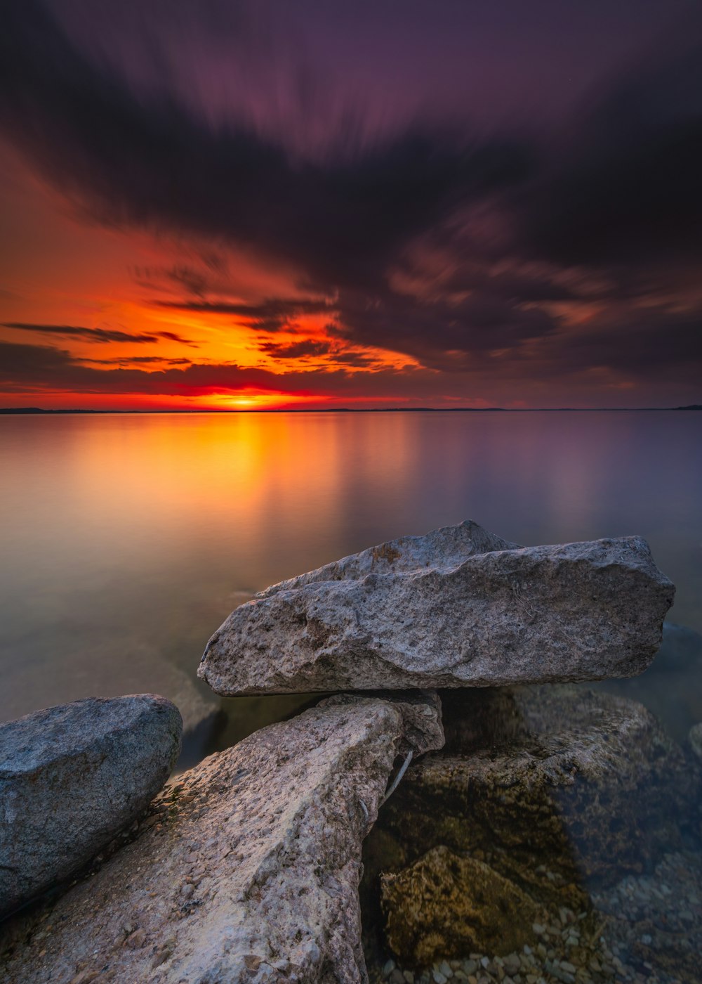 gray and black rocks near body of water during sunset