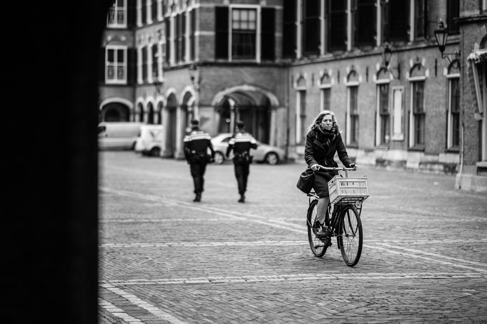 grayscale photo of woman riding bicycle on road