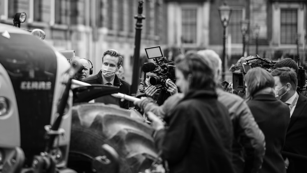 grayscale photo of man in black coat holding camera