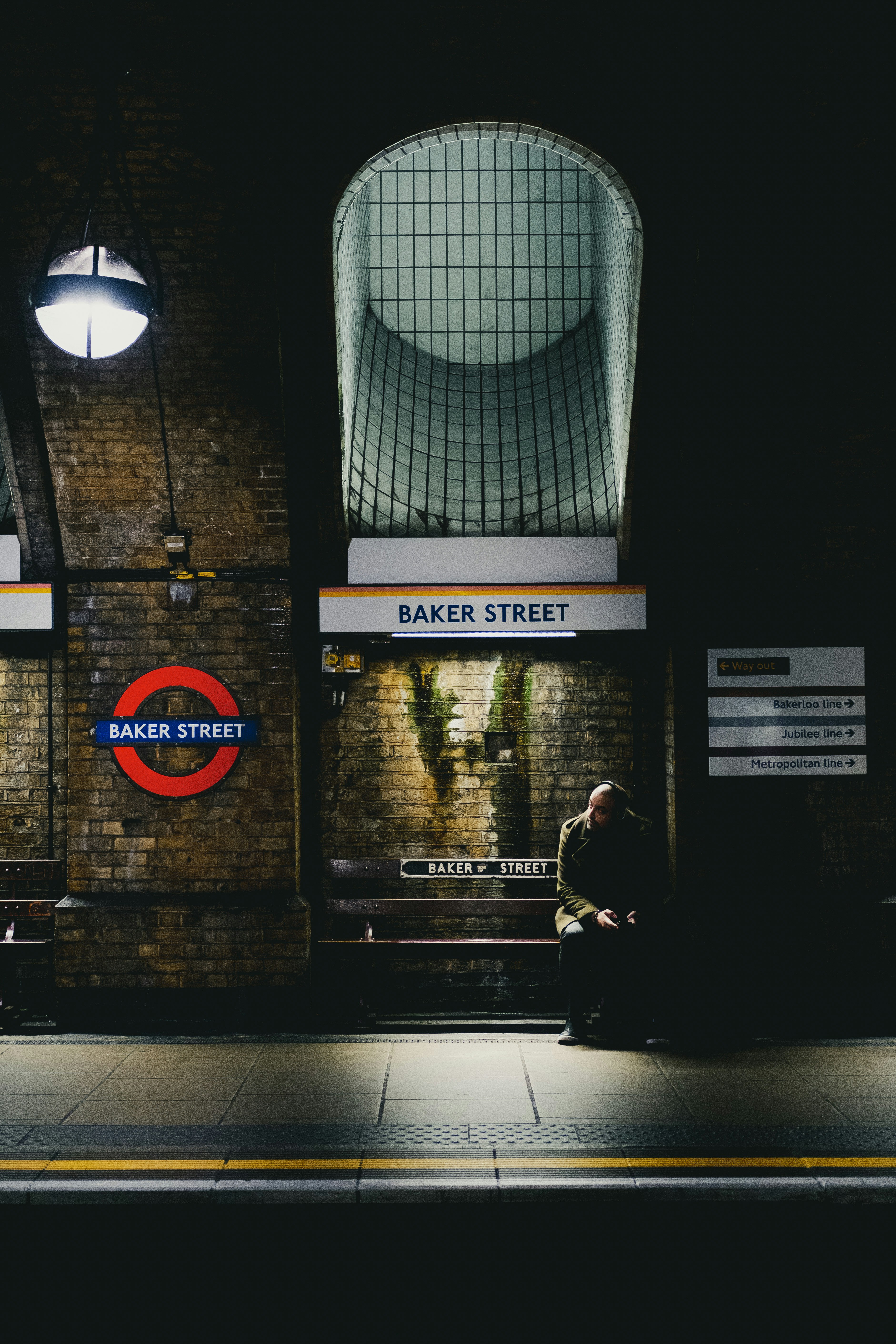 man in sitting on a platform bench at Baker Street underground station