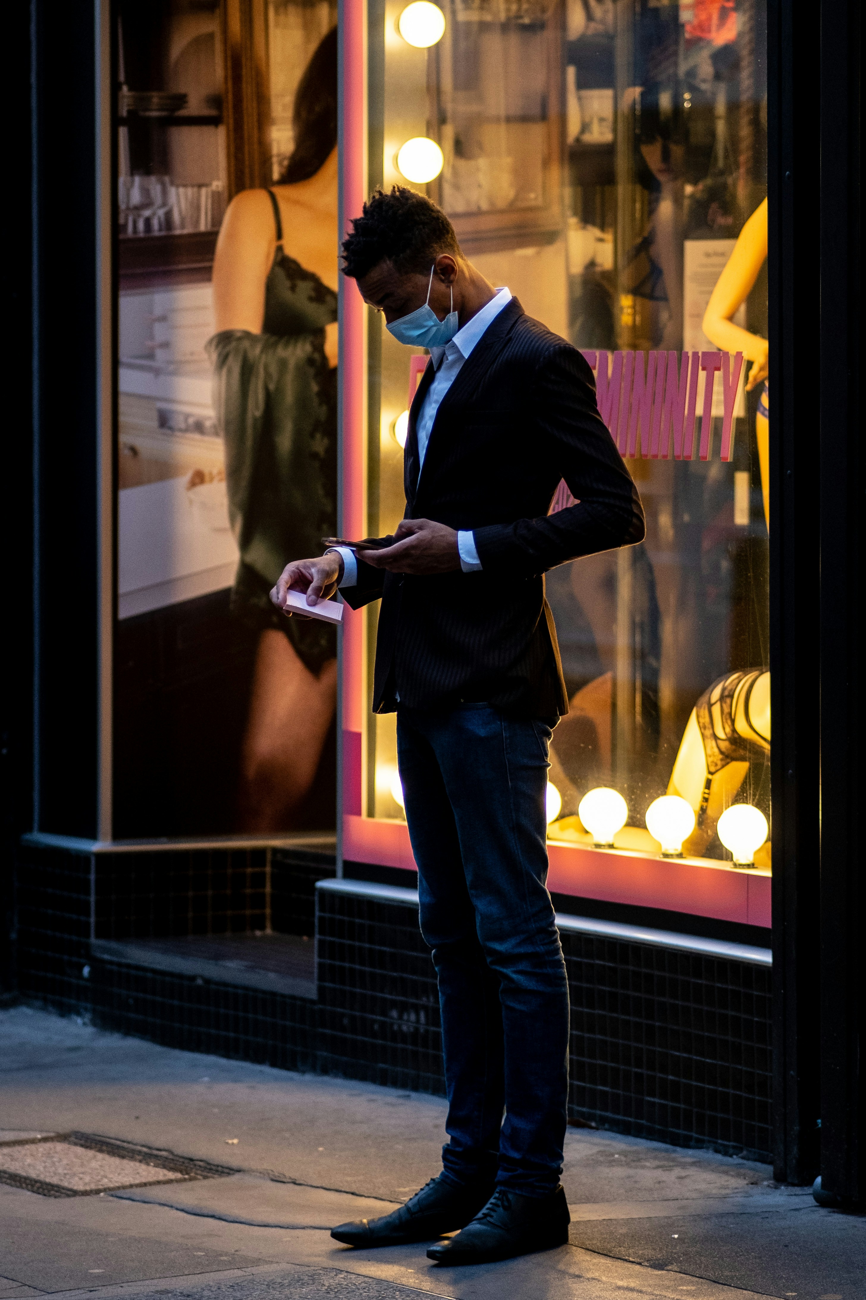 man in black suit jacket and blue denim jeans standing beside woman in yellow sleeveless shirt