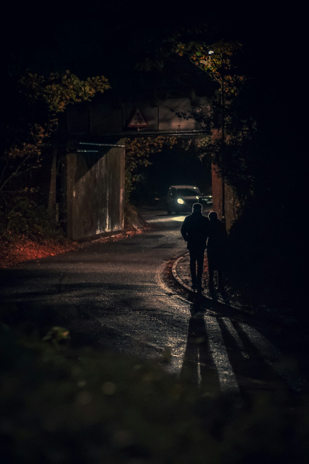 Mann in schwarzer Jacke geht nachts auf der Straße spazieren