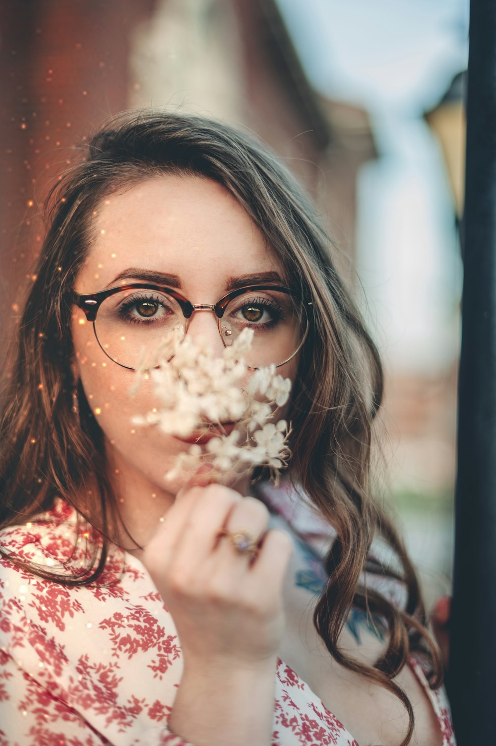 woman in white and pink floral shirt holding white flower