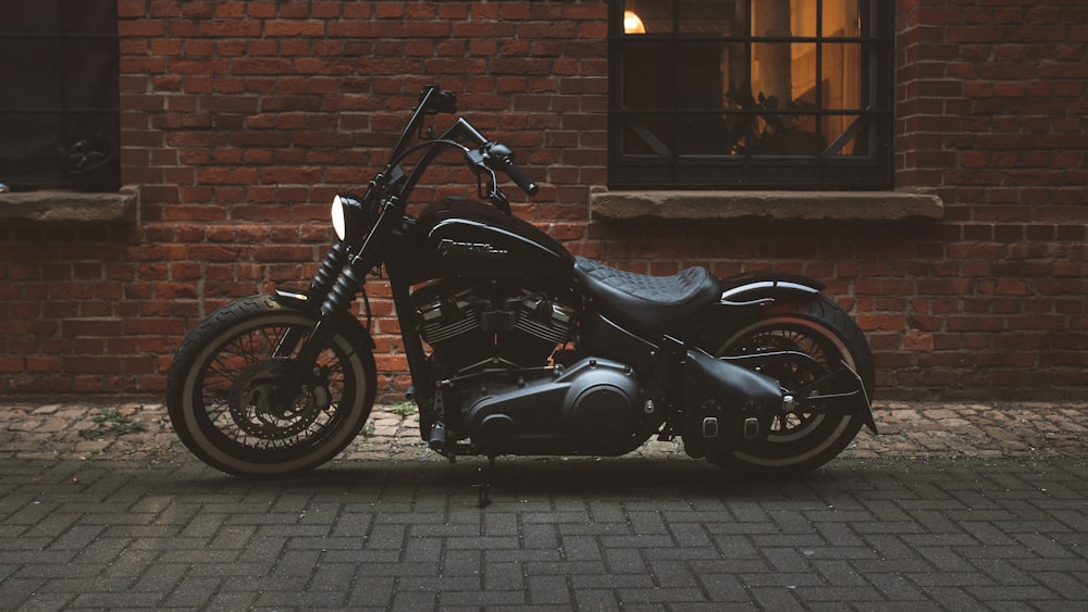 black and gray motorcycle parked beside brown brick wall