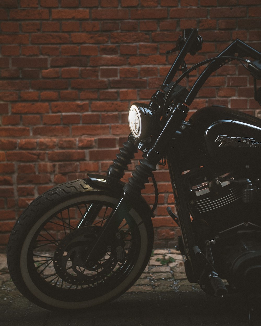 black motorcycle parked beside brown brick wall