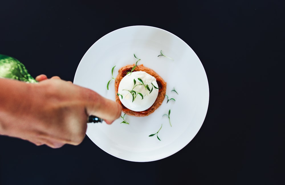 person holding white round plate with green and yellow vegetable