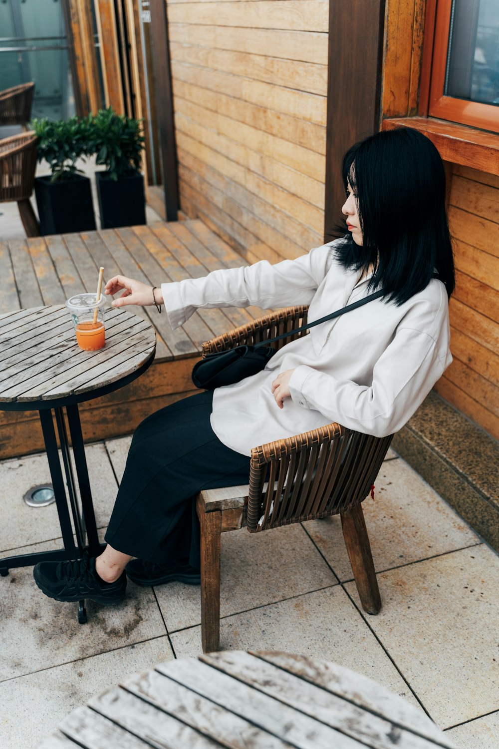 woman in white long sleeve shirt and black pants sitting on brown wicker chair