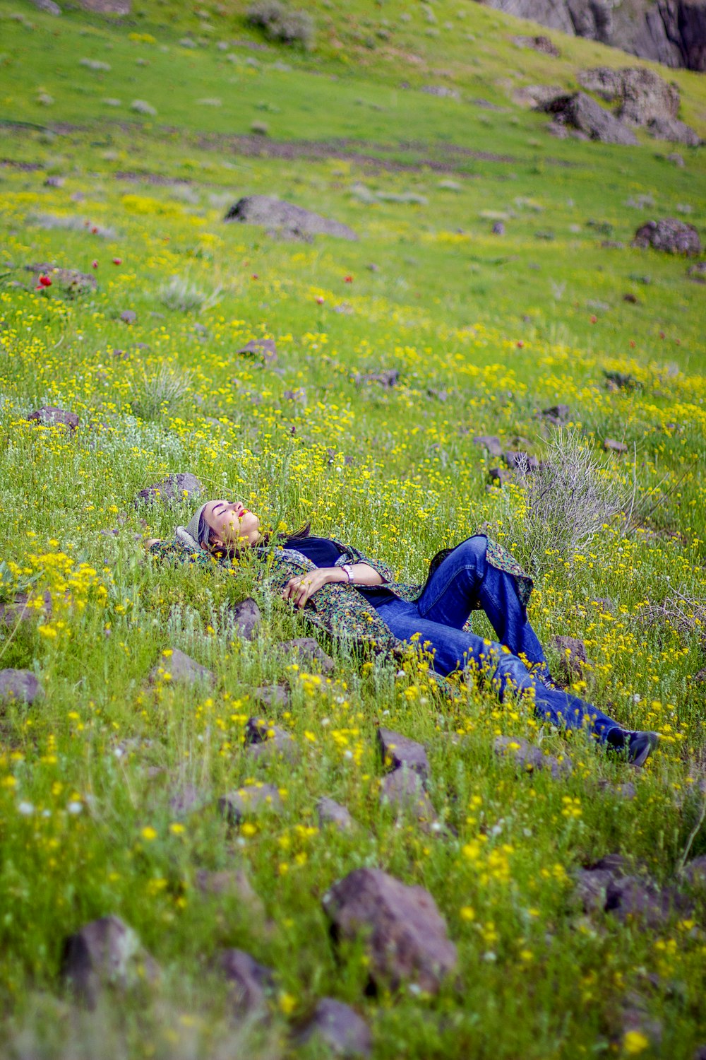 man in black jacket lying on blue blanket on green grass field during daytime