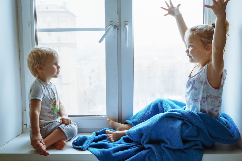 boy in white and green crew neck t-shirt sitting on blue textile