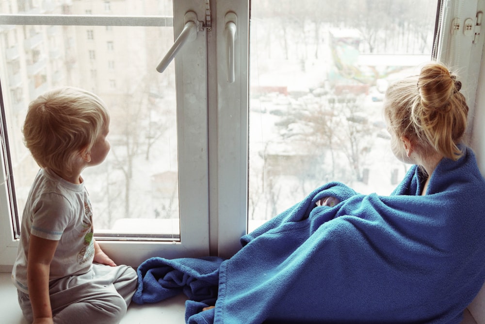 girl in white and gray long sleeve shirt sitting beside boy in blue shirt