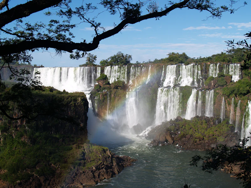 Quedas das Cataratas do Iguaçu cercadas pela mata, com arco-íris na névoa