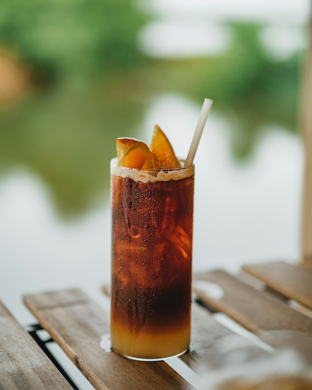 clear drinking glass with brown liquid on brown wooden table