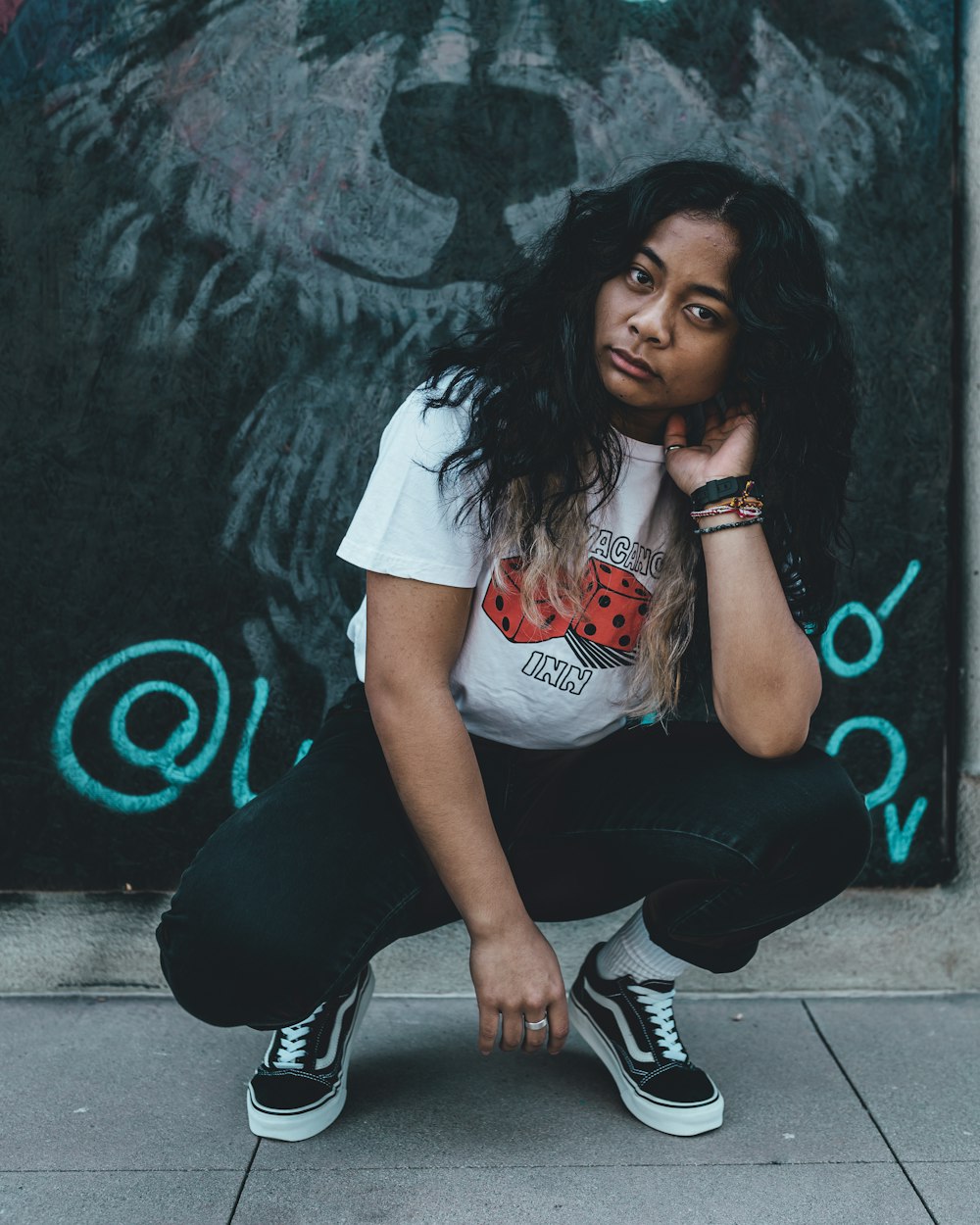 woman in white t-shirt and black pants sitting on concrete floor