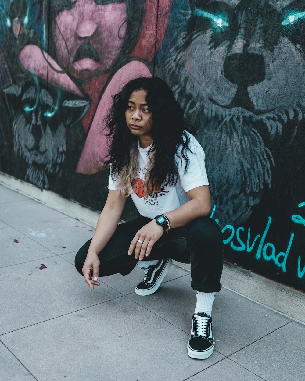 woman in white t-shirt and black pants sitting on concrete floor