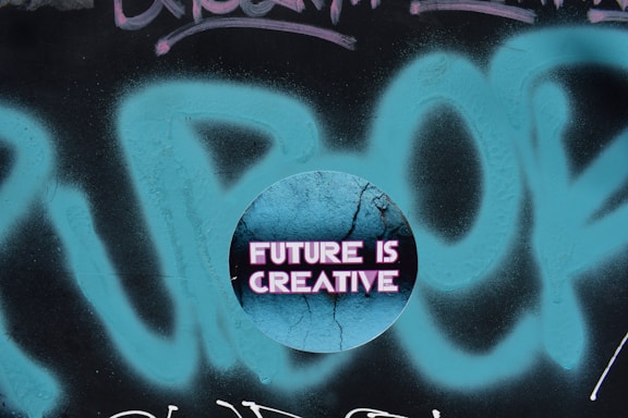 A circular graphic overlays a graffiti background with the phrase 'FUTURE IS CREATIVE' displayed in bold, neon pink letters on a cracked, textured blue surface.