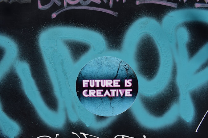 A circular graphic overlays a graffiti background with the phrase 'FUTURE IS CREATIVE' displayed in bold, neon pink letters on a cracked, textured blue surface.