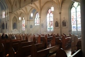 Peaceful interior of the church sanctuary with wooden pews and stained glass.